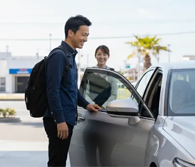 スタッフと利用者が車両をチェックして引き渡す場面